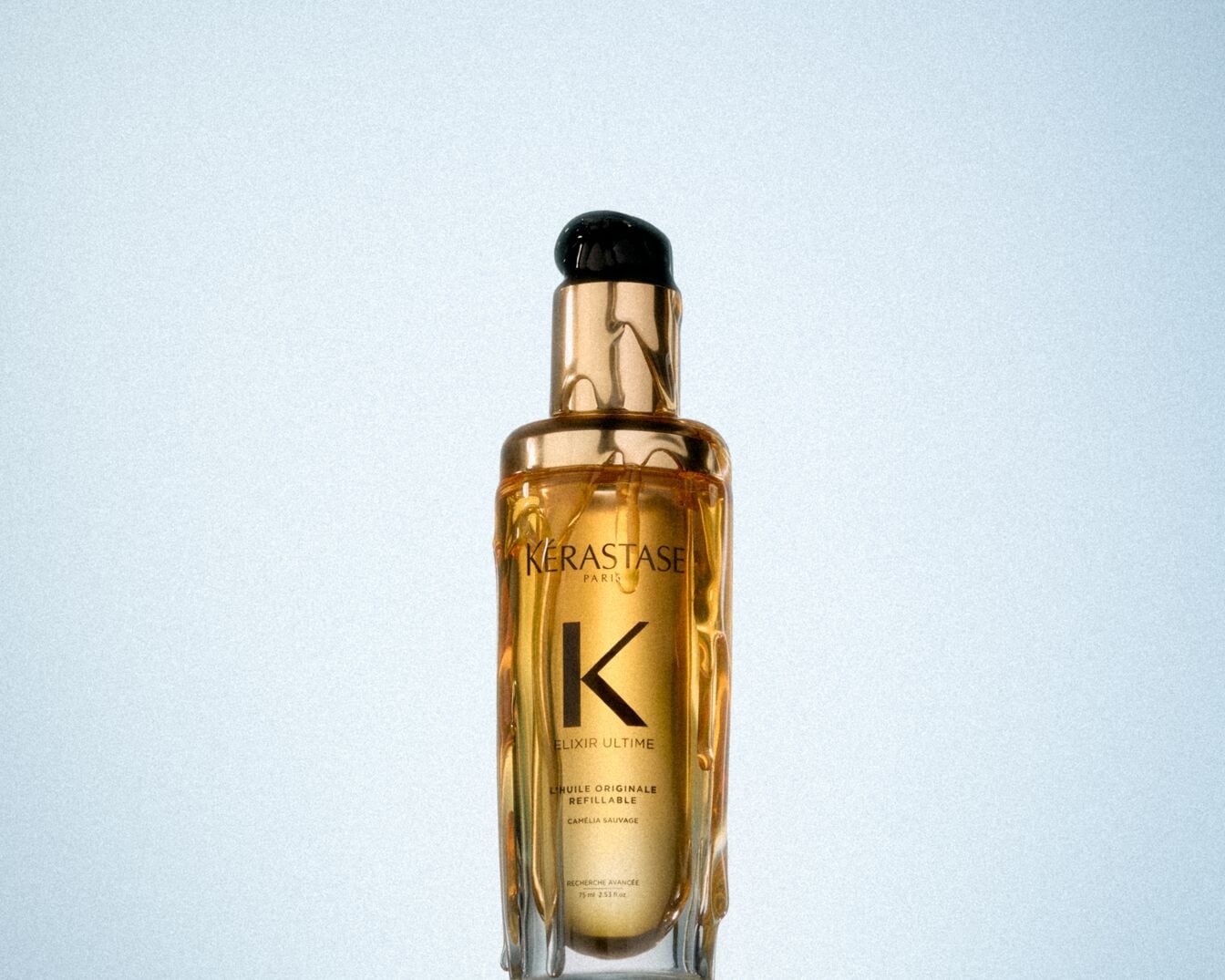 Tuvplānā K&Eacute;RASTASE &ldquo;Elixir Ultime L'Huile Originale&rdquo; eļļa matiem zeltainā pudelē ar melnu vāciņu.