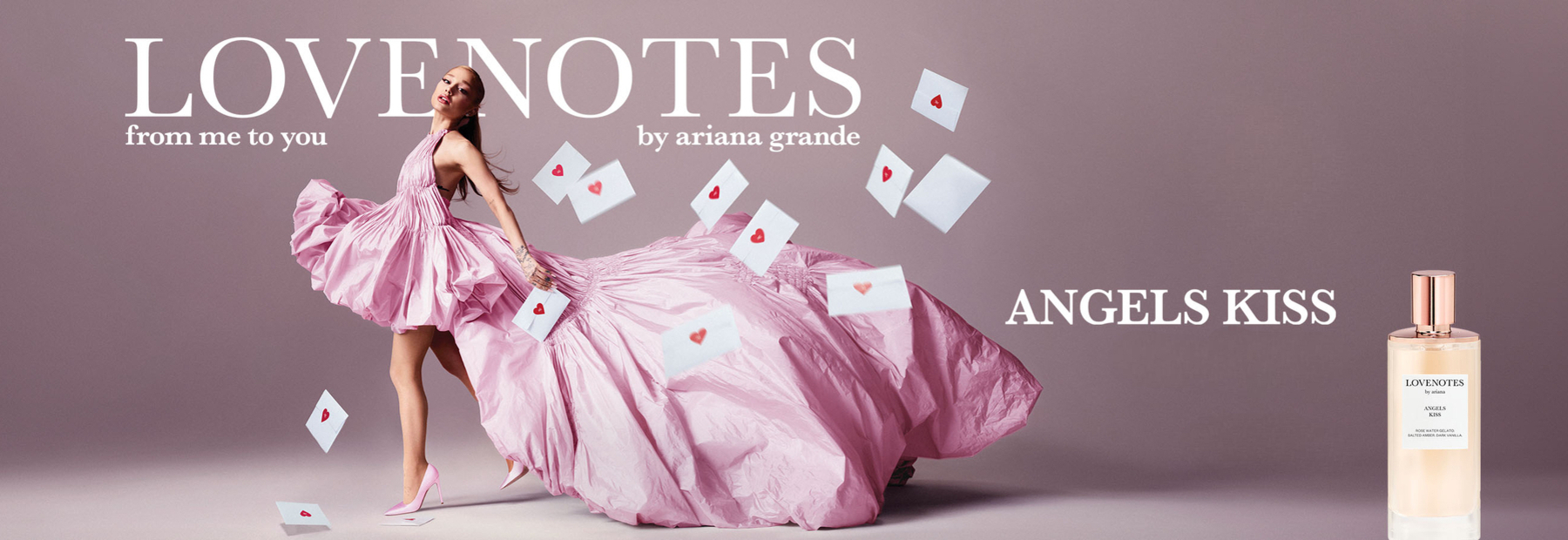 Ariana Grande roosas kleidis “LOVENOTES: Angels Kiss” parfüümi reklaamil, ümber lendlevad südamekujulised armastuskirjad ja paremal pudel parfüümiga.